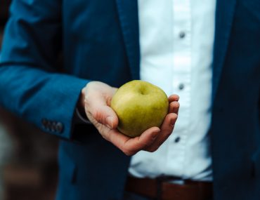 Mann hält einen grünen Apfel ins Bild